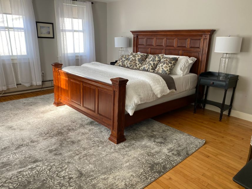 a bed with a wood frame and a lamp on a rug