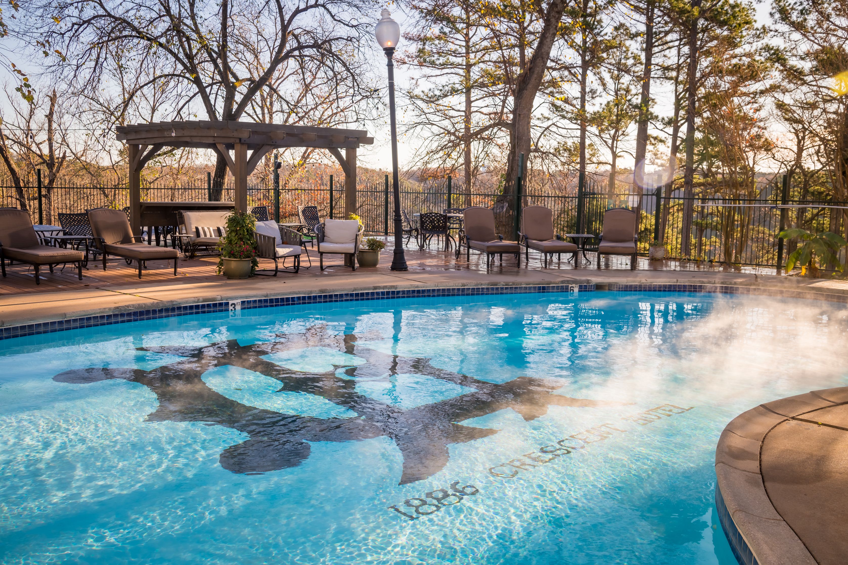 a pool with chairs and a table and a lamp