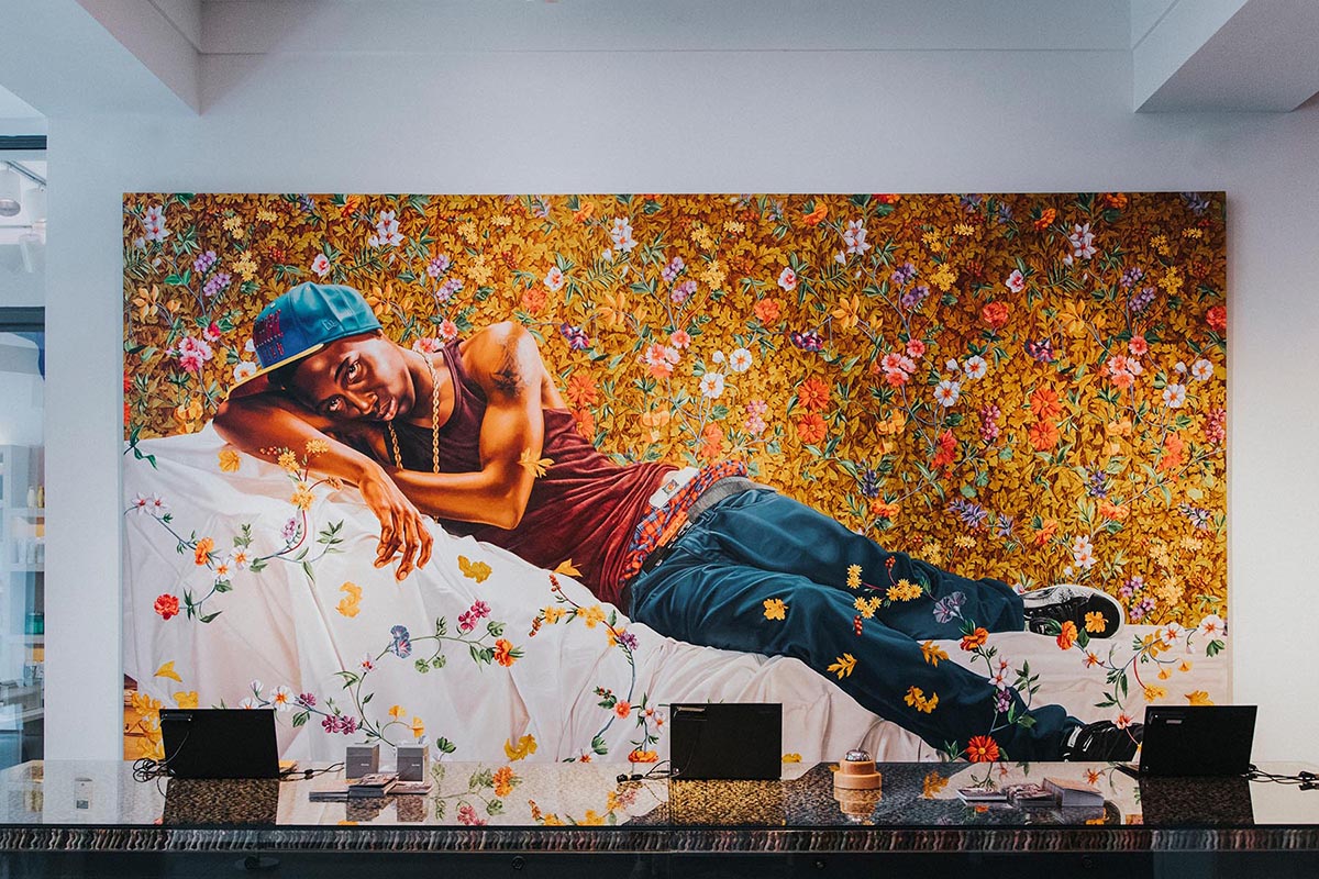 a man lying on a bed with flowers on the wall
