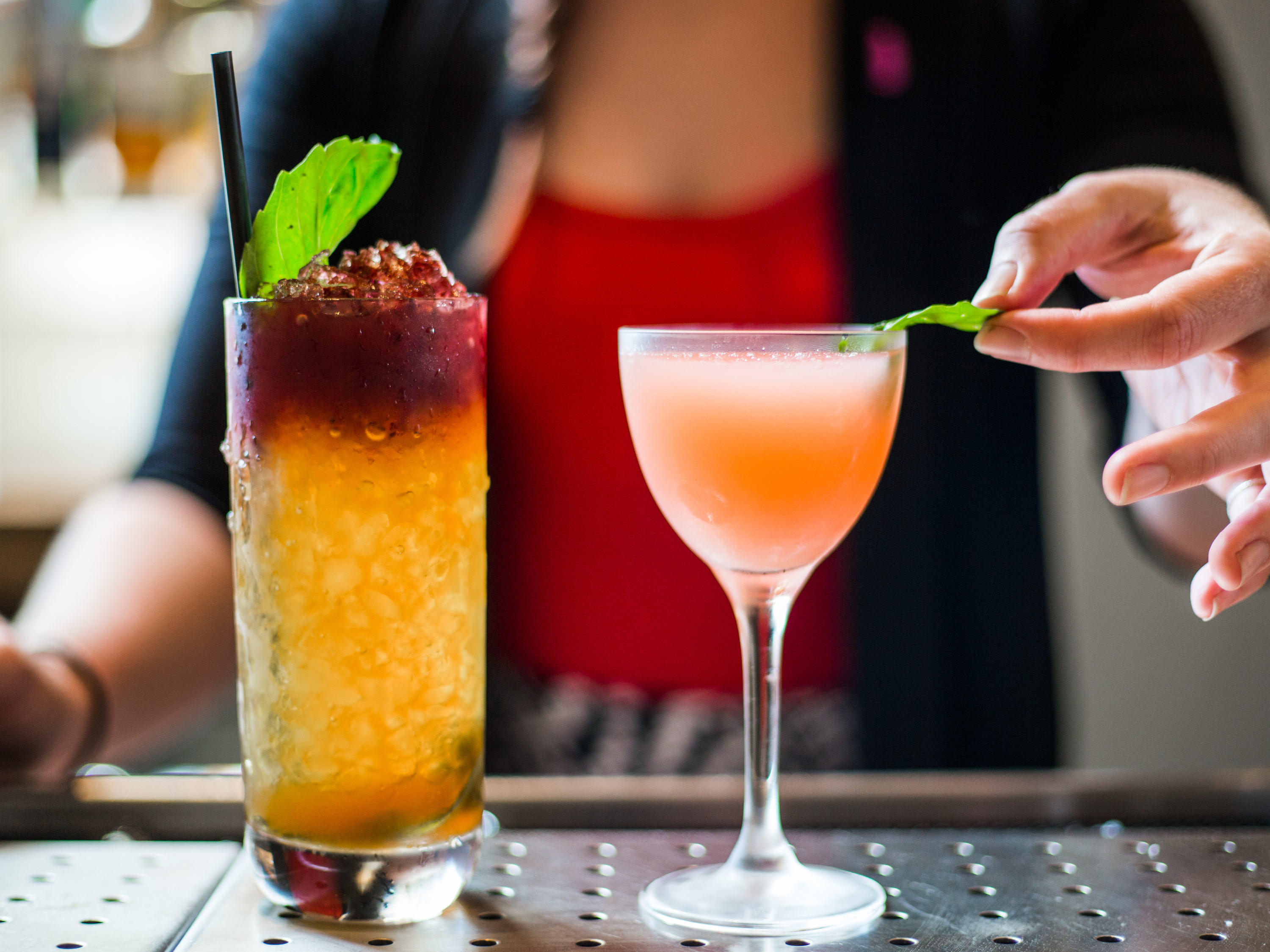 a person holding a leaf of a drink next to a glass