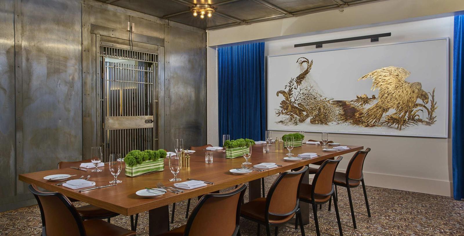 a long table with glasses and plates in a room with a painting