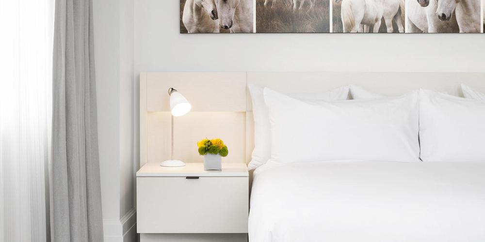 a white bed with a lamp and flowers