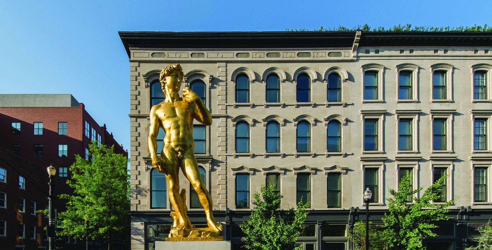 a statue of a naked man with a glass of wine in front of a building