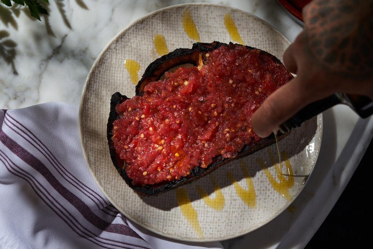 a person pouring oil onto a piece of bread