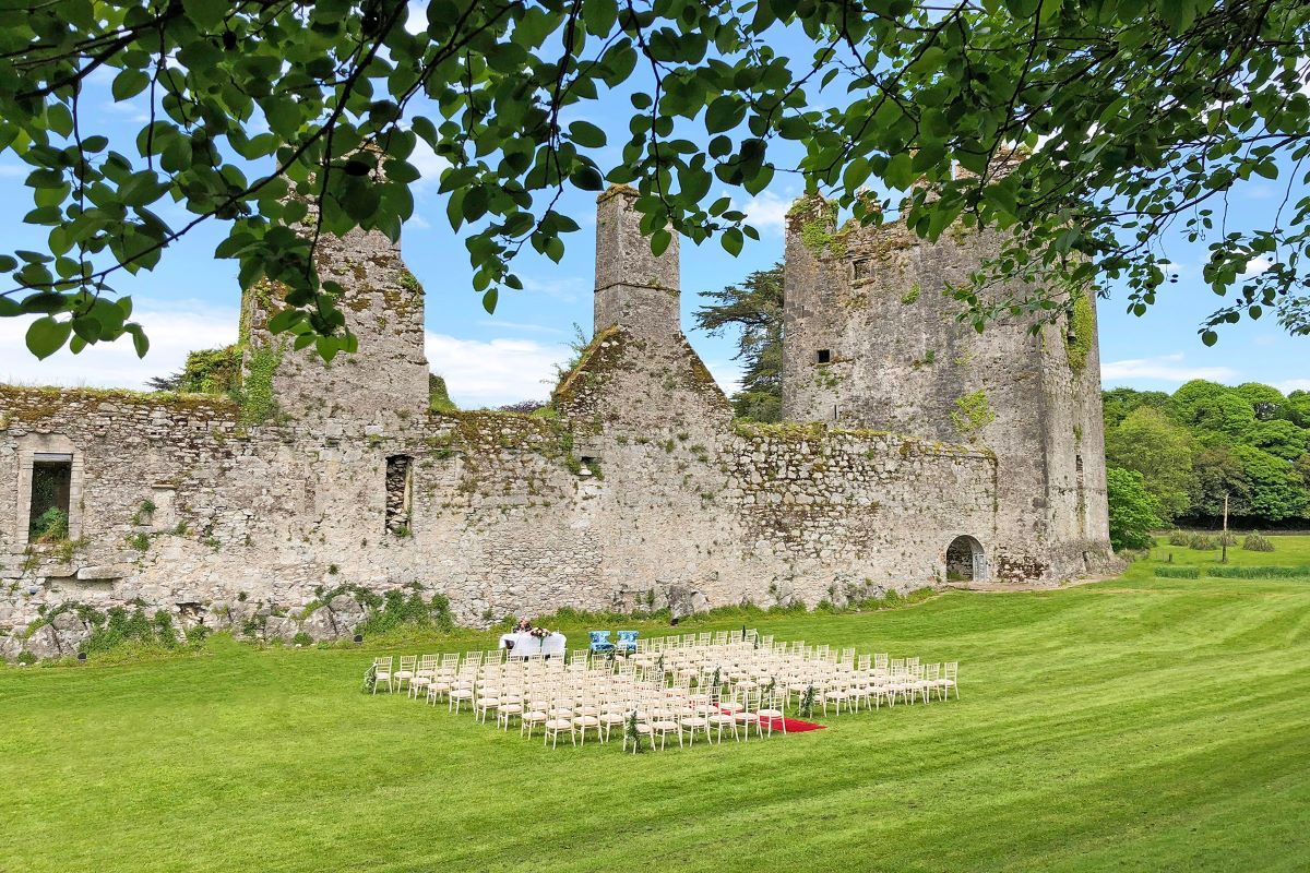 a group of chairs in a field with a stone building in the background