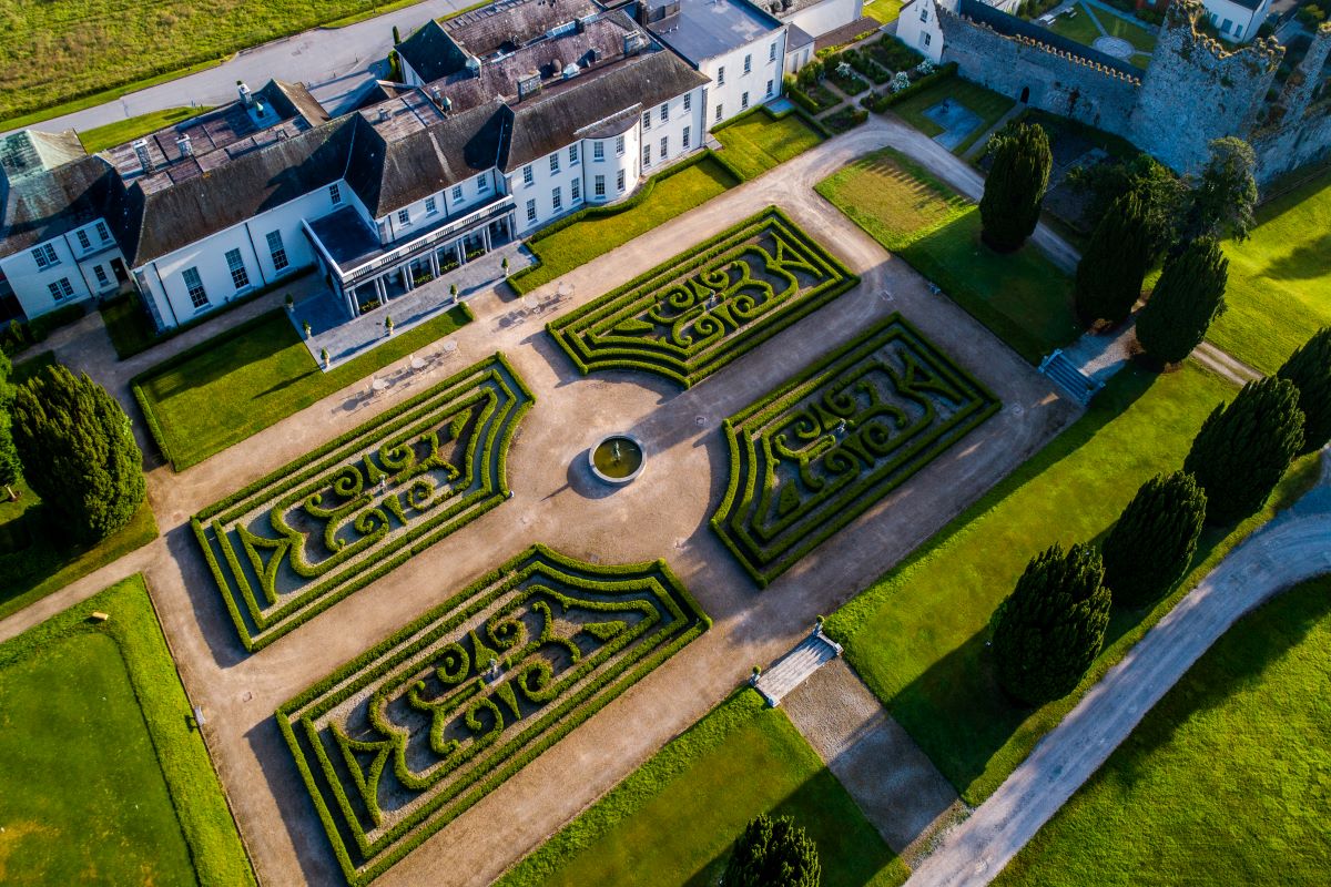 a large garden with a large building and a stone wall
