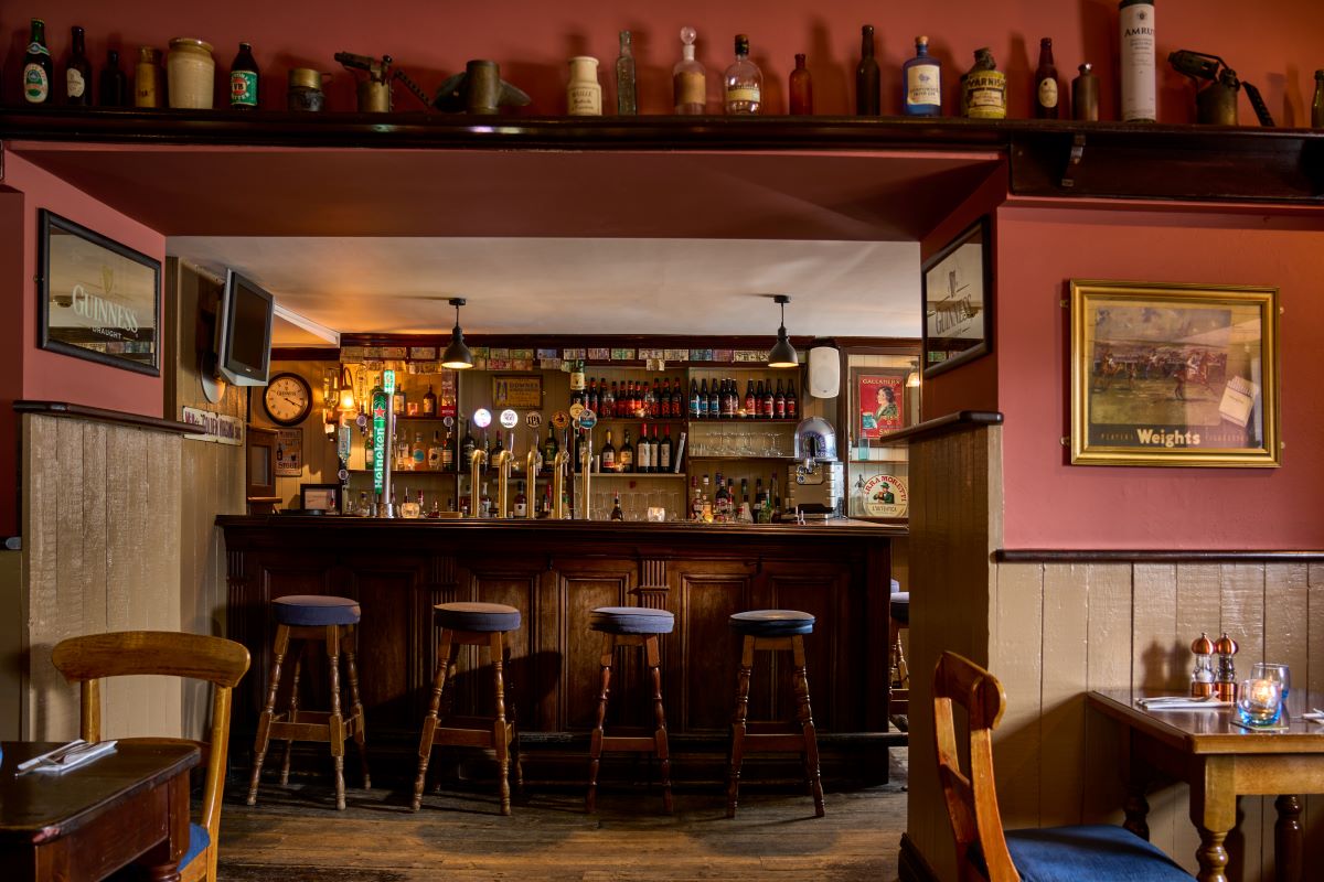 a bar with a row of bottles on the wall