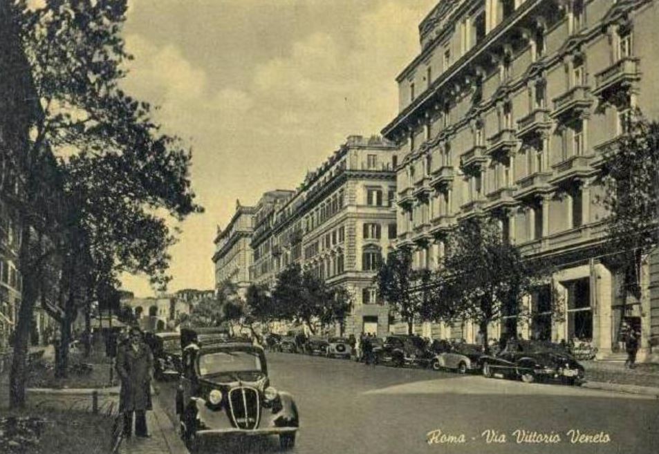 a black and white photo of a street with cars and buildings