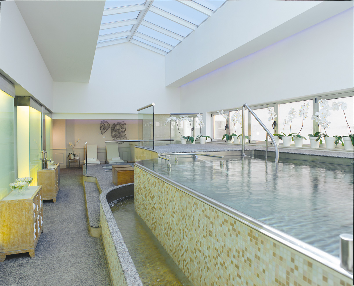 a large indoor pool with a glass wall and a large tub