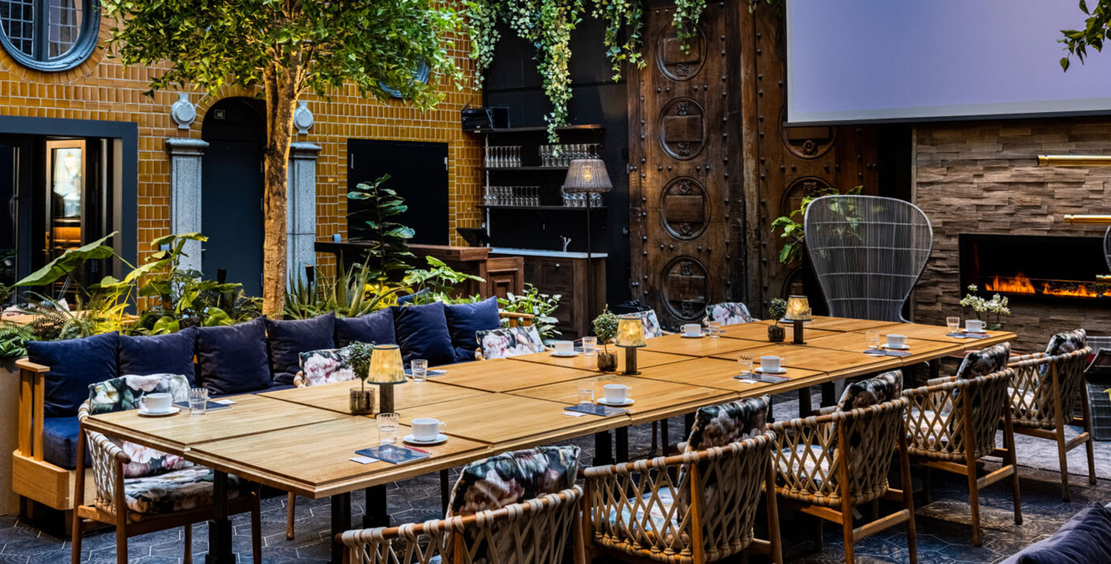 a large table with chairs and a screen in the background