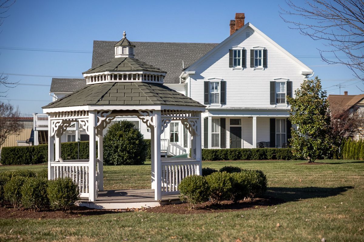 a white gazebo in a yard with a house in the background