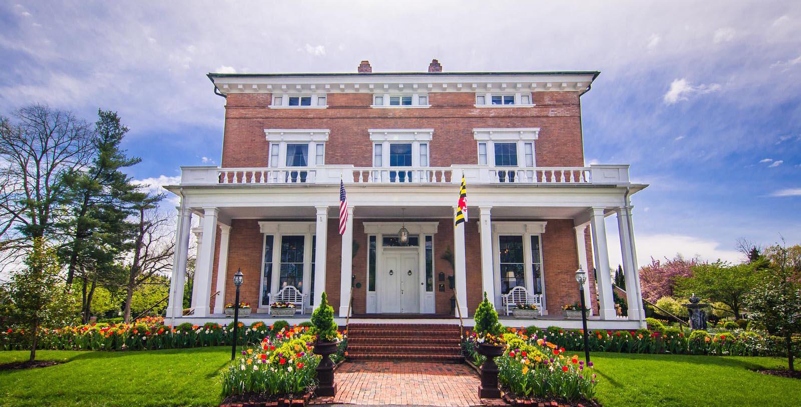 a large brick house with flags and flowers