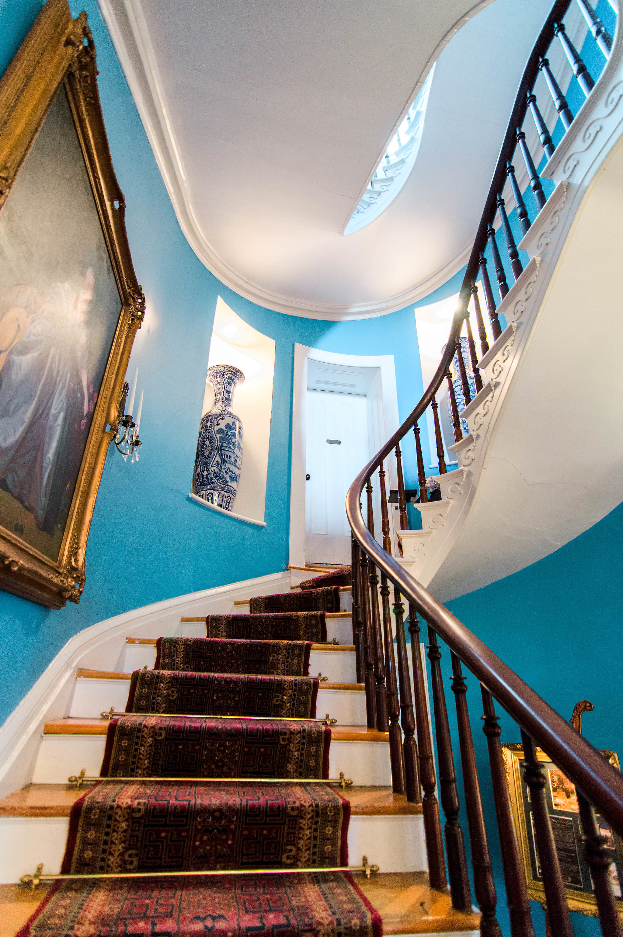 a staircase with a blue wall and a painting on the wall