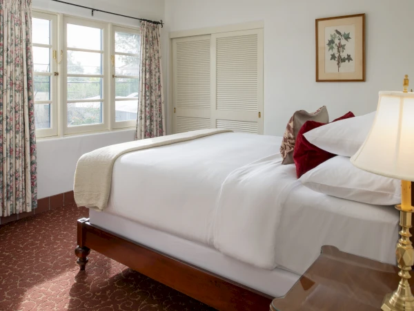 a bed with white sheets and red pillows