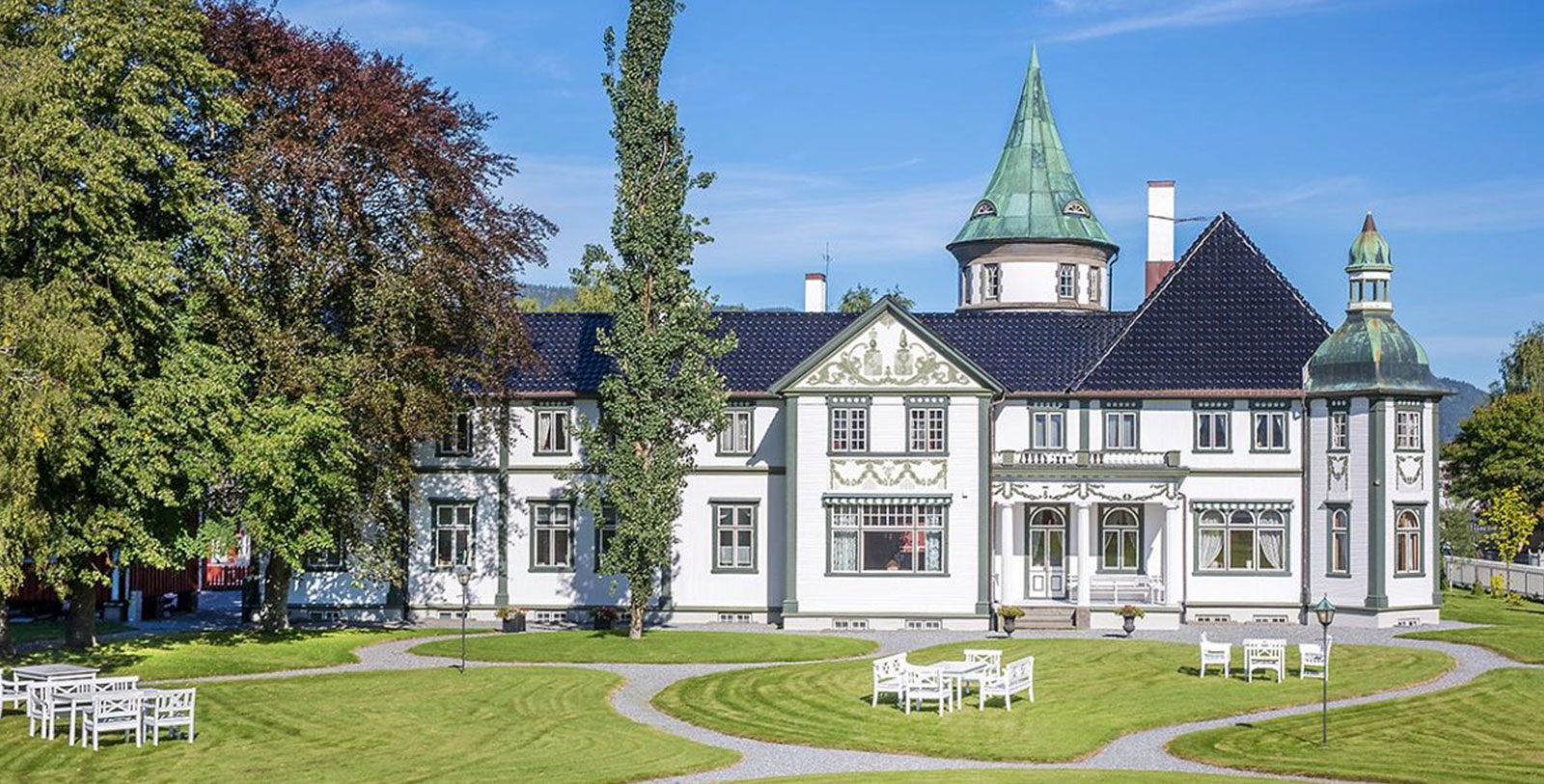 a white house with a lawn and a tree