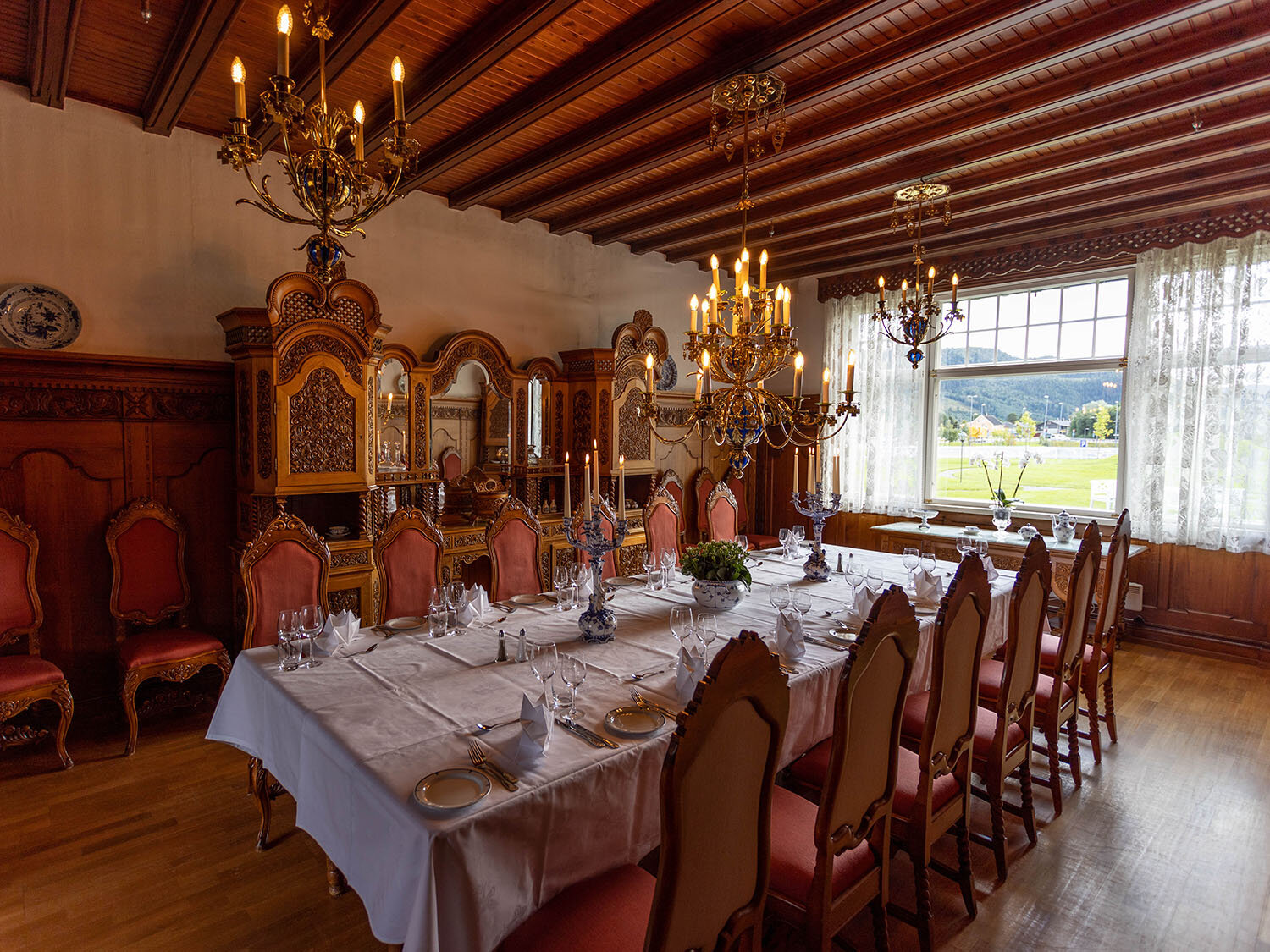 a large dining room with a table set and chandeliers
