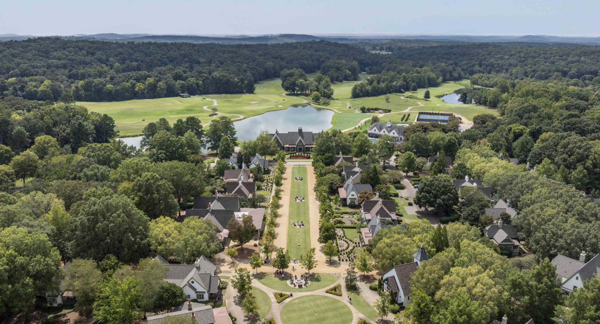 a aerial view of a golf course with a group of houses and a pond
