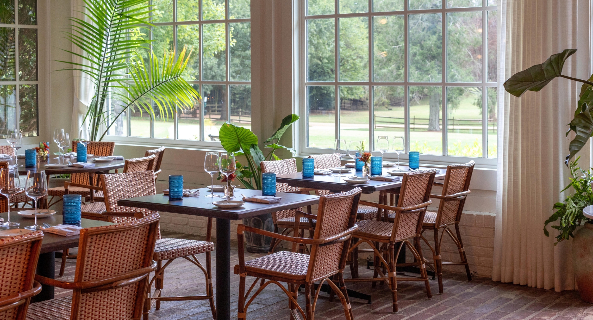 a table with blue glasses and plates in a room with windows