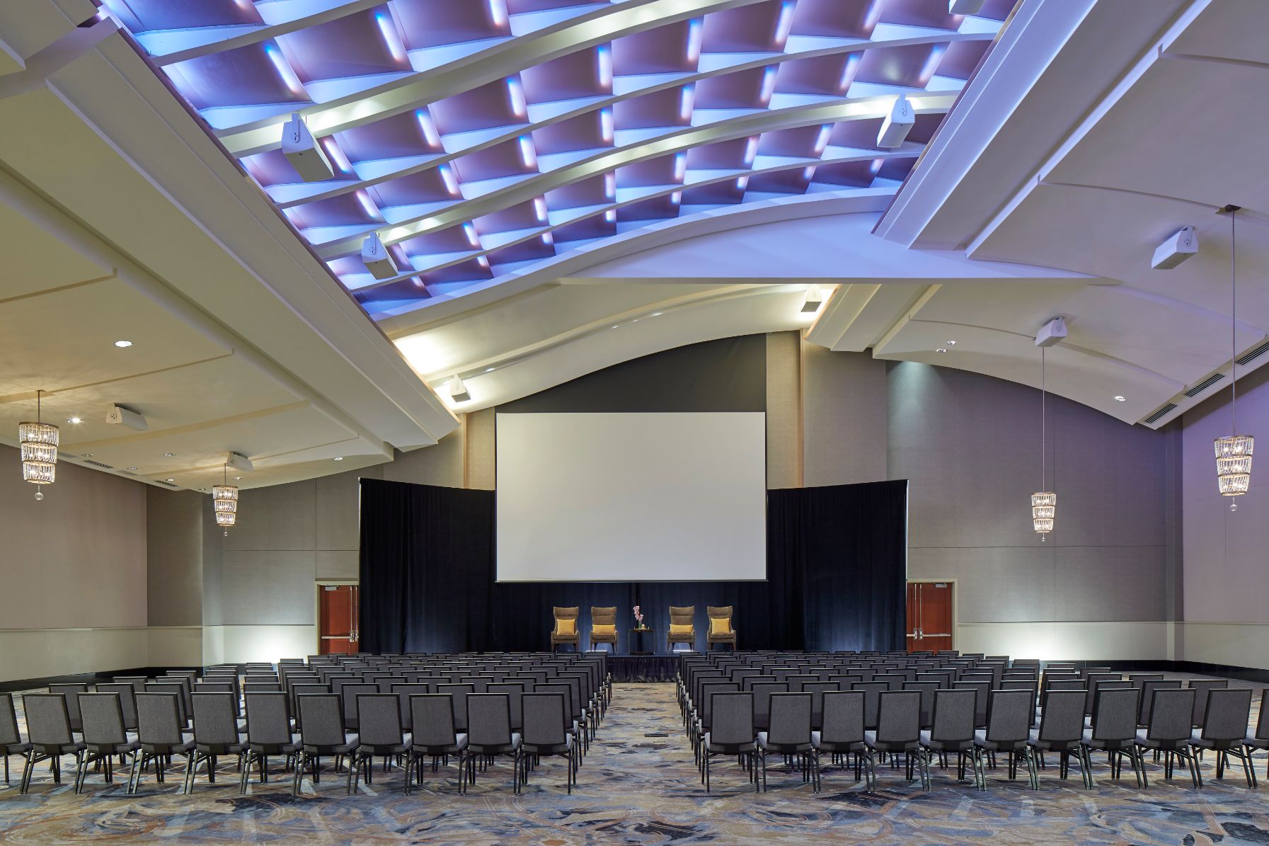 a room with a large screen and chairs