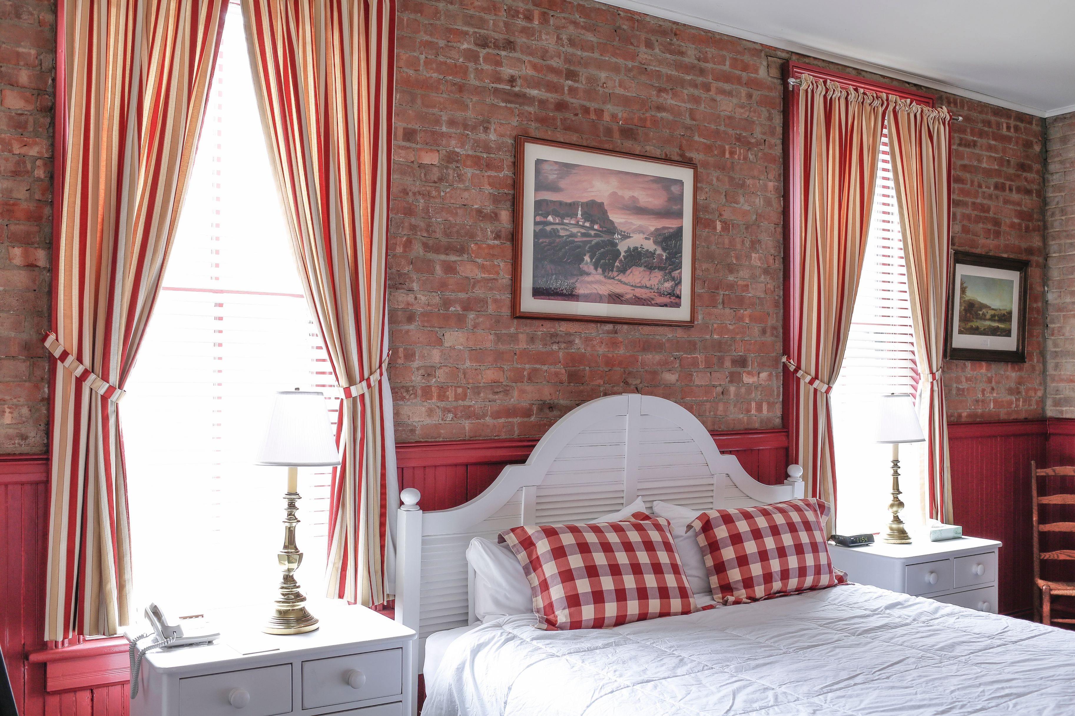 a bed with red and white plaid pillows and a lamp on a nightstand