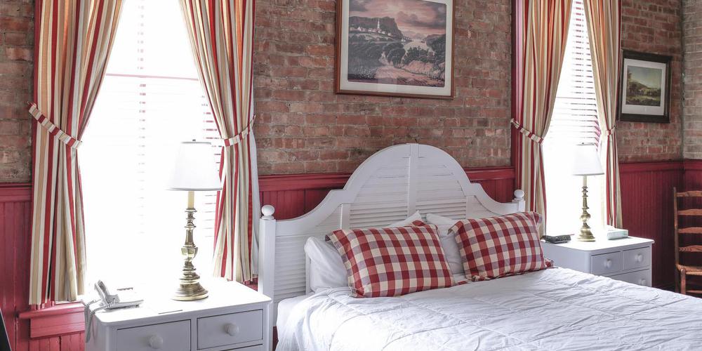 a bed with red and white plaid pillows and a lamp on a nightstand