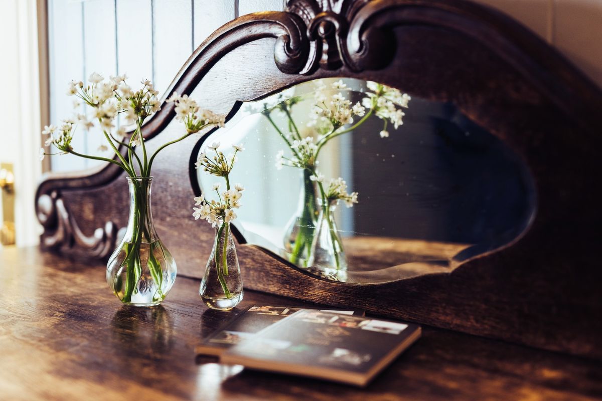 a vases of flowers in front of a mirror
