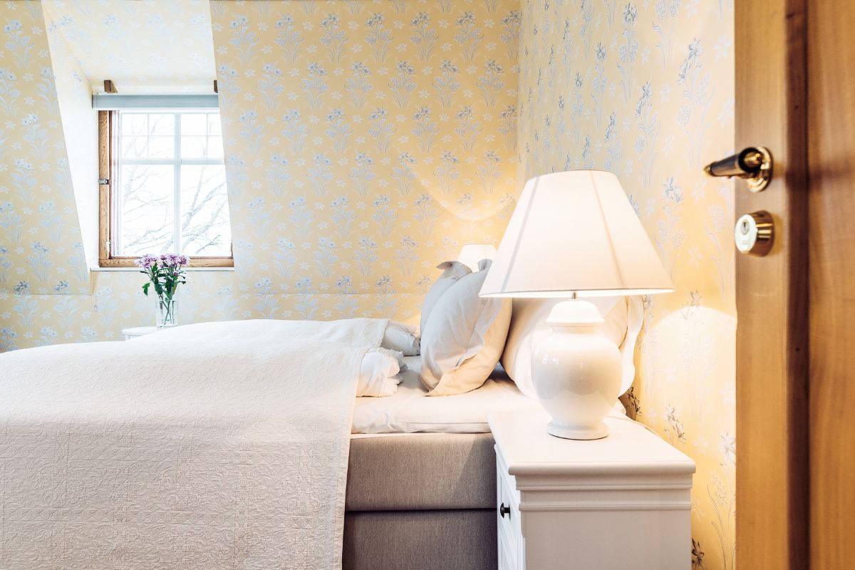 a bed with a white bedding and a lamp on a nightstand