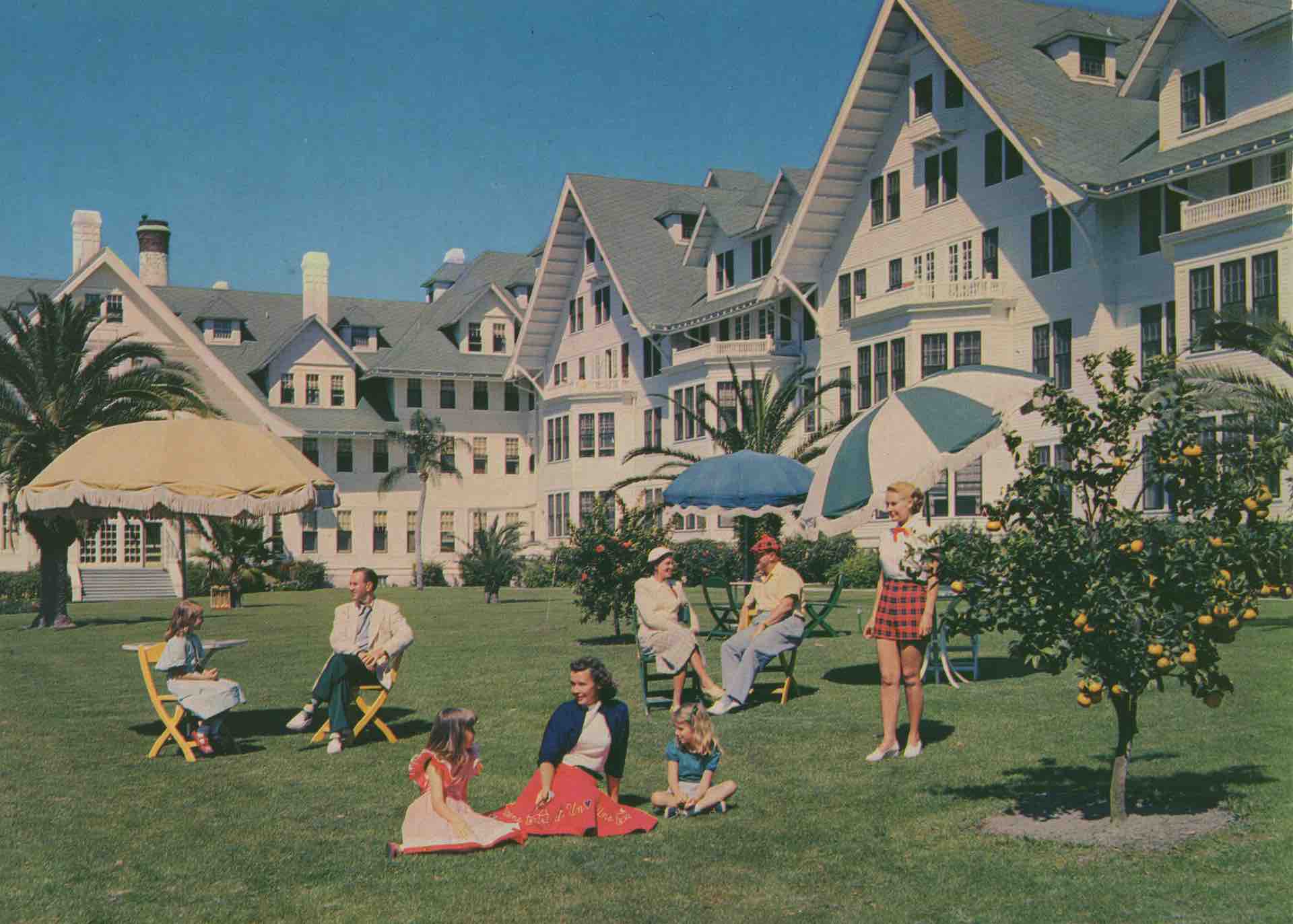 a group of people sitting on grass in front of a large white building