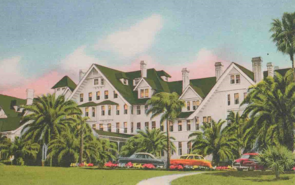 a large white building with palm trees and flowers