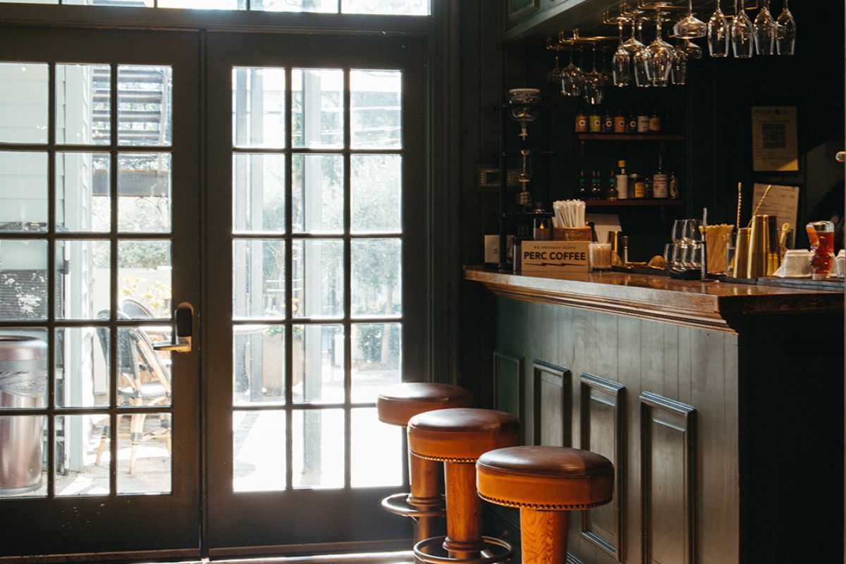a bar with stools and glasses in front of a door