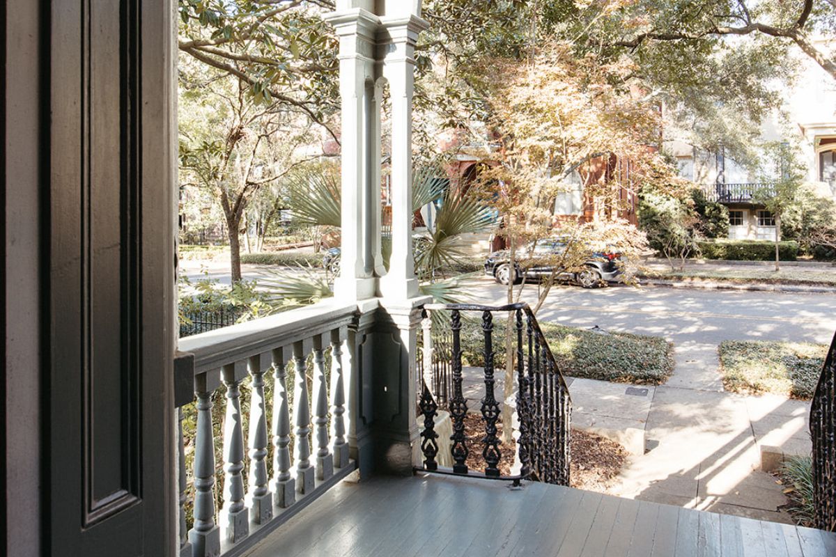 a porch with a railing and trees in the background