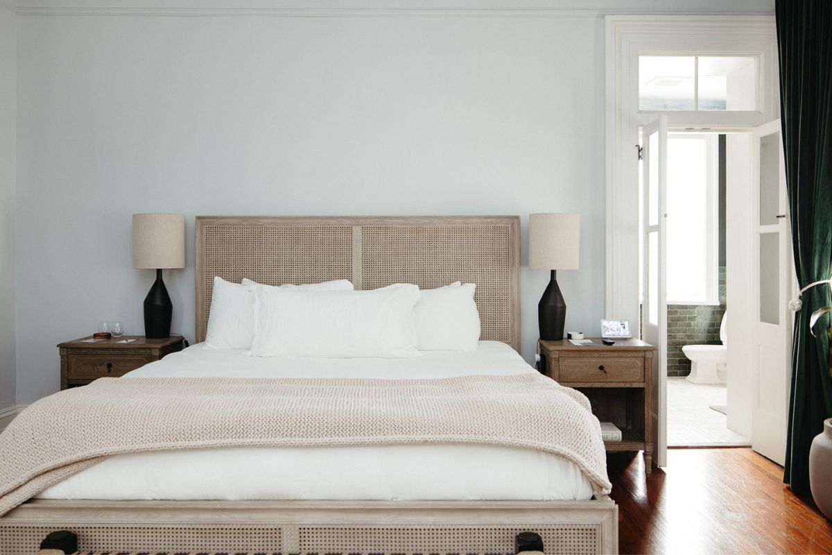 a bed with a wicker headboard and lamps