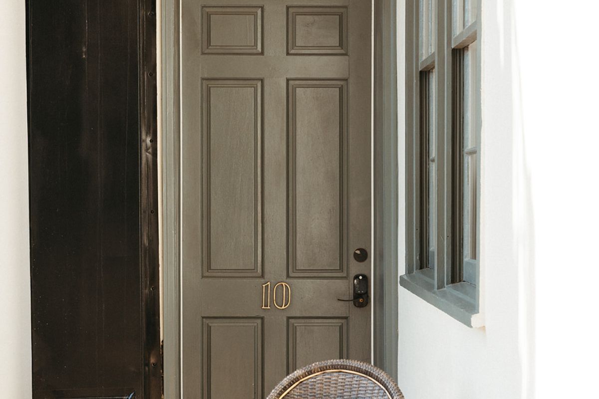 a grey door with a black handle and a wicker chair