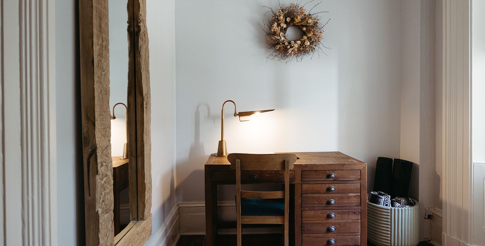 a desk with a lamp and a wreath on the wall