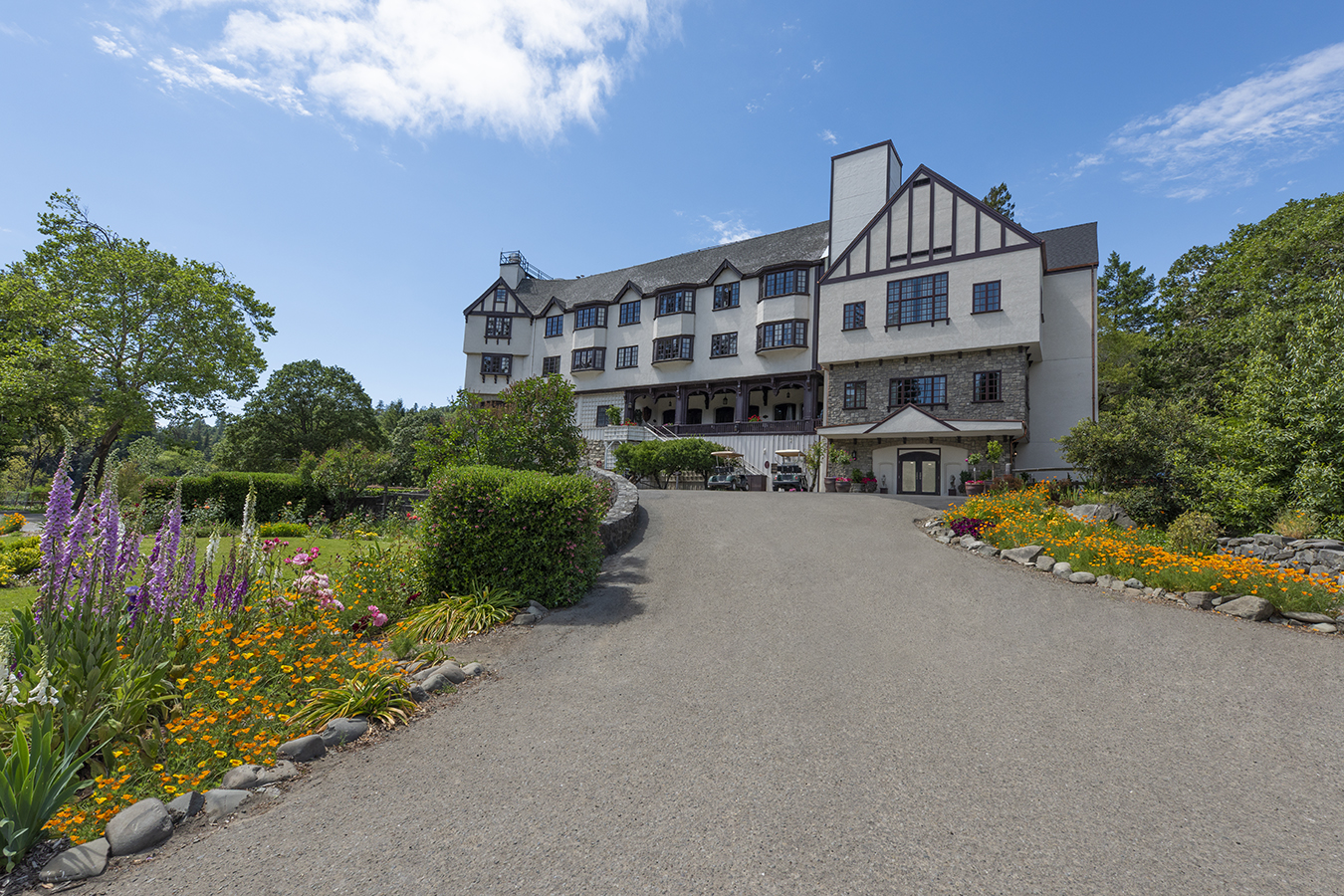 a large building with a driveway and flowers