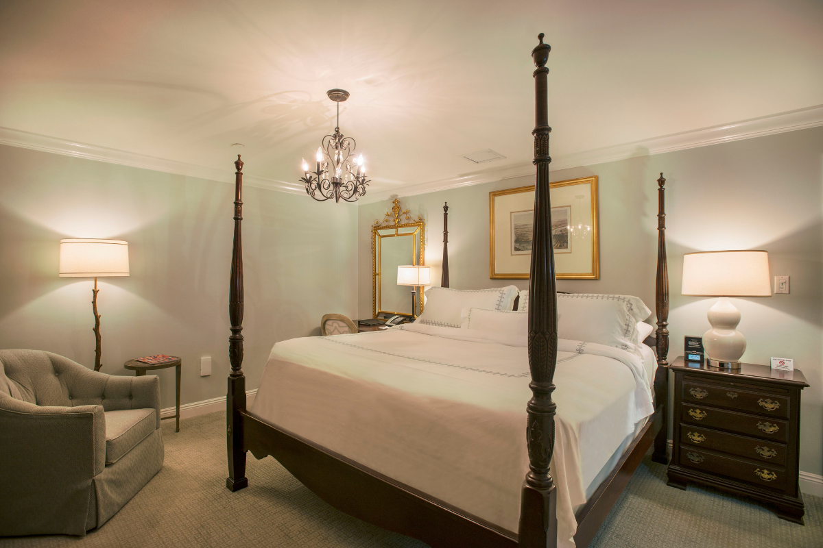 a bedroom with four poster bed and chandelier