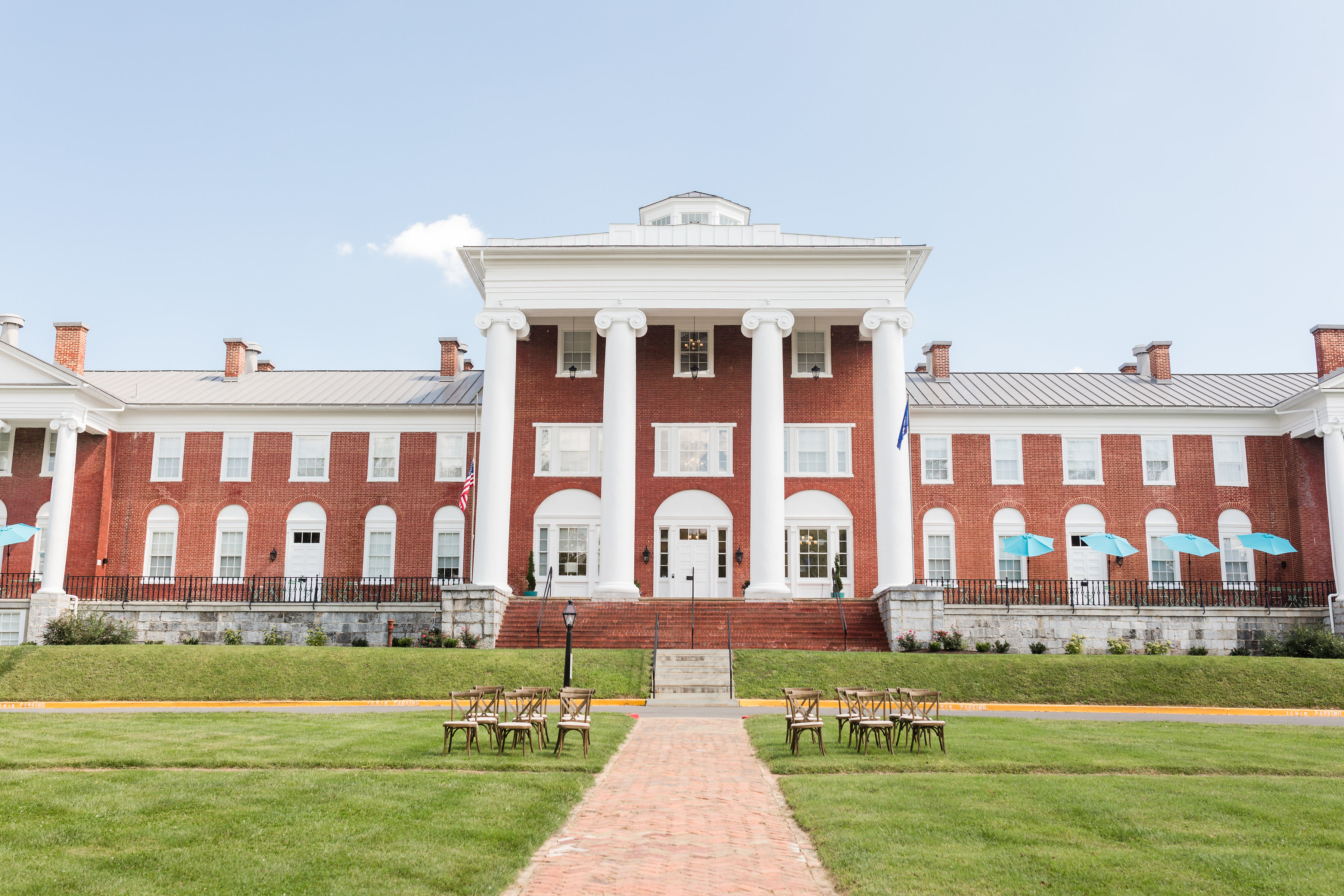a brick building with columns and chairs in front of it