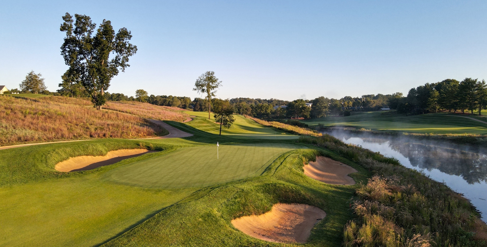 a golf course with sand bunkers and a lake