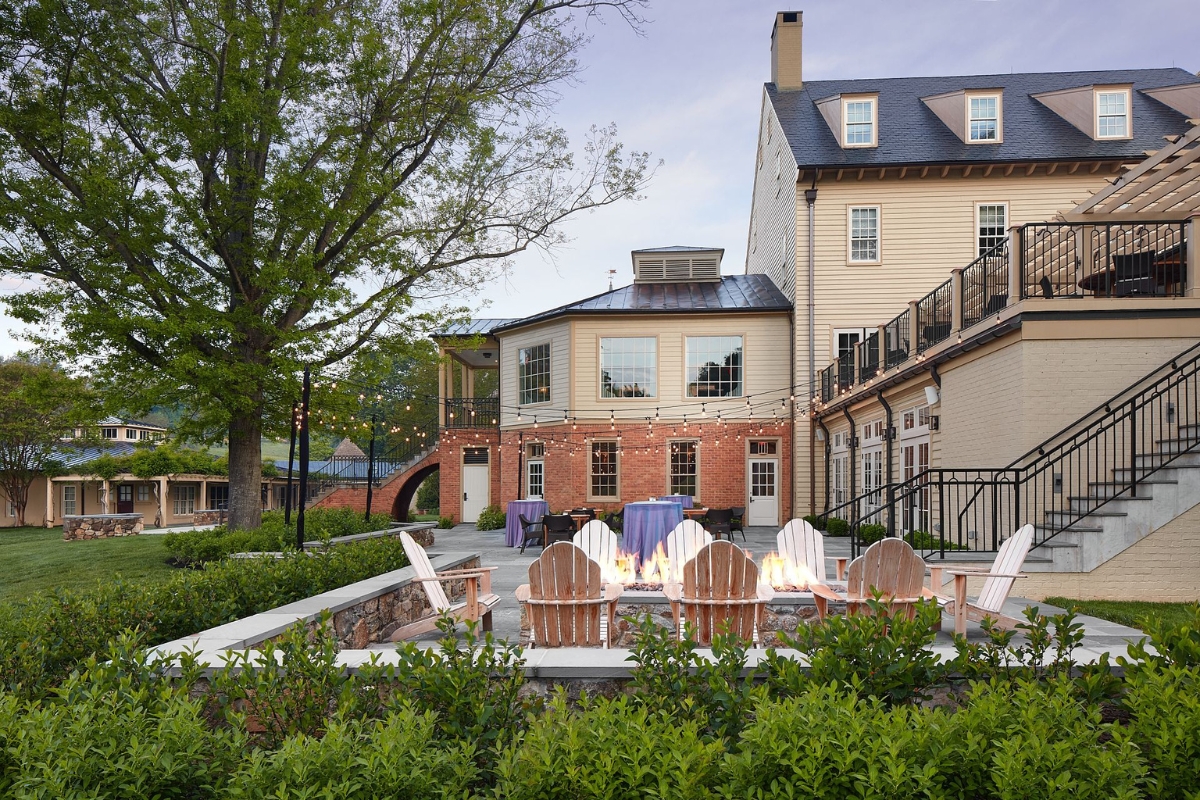 a patio with chairs and a fire pit in front of a building