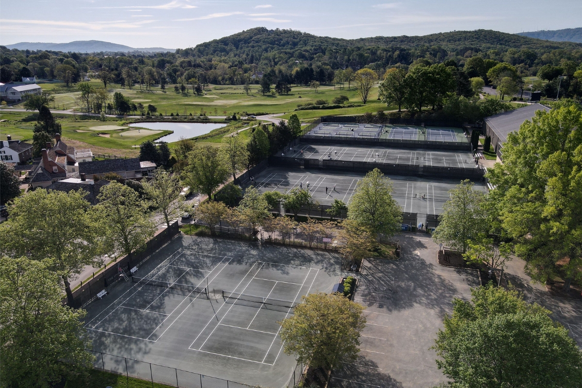 tennis courts with trees and a river in the background