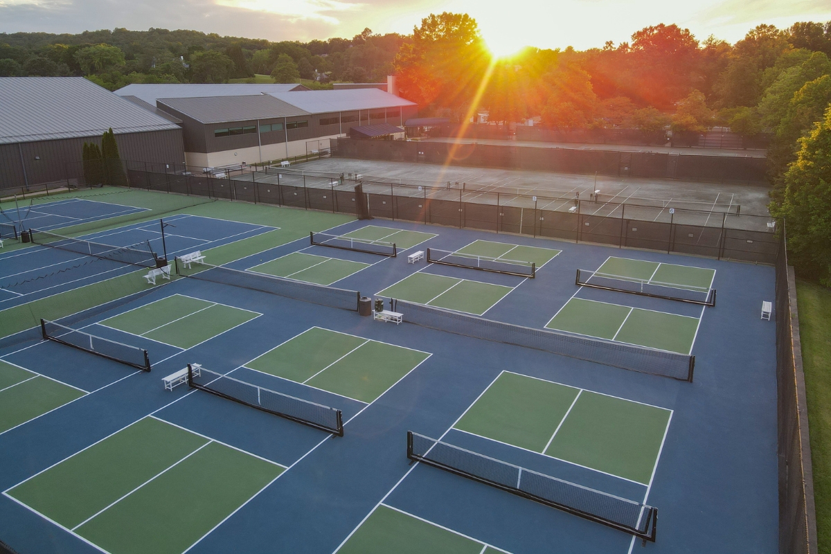 a tennis courts with a fence and trees in the background