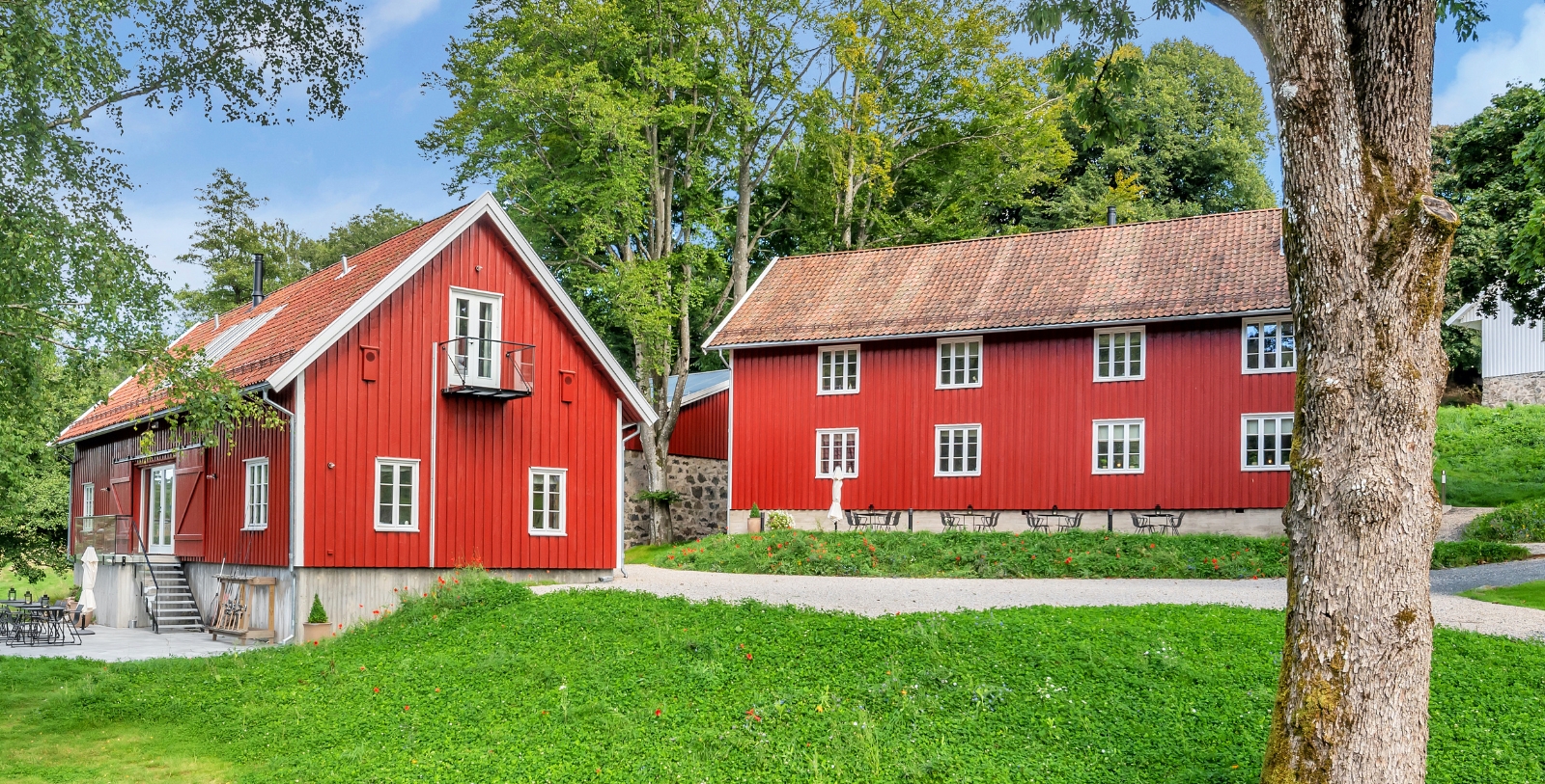a red house with a lawn and trees in the background