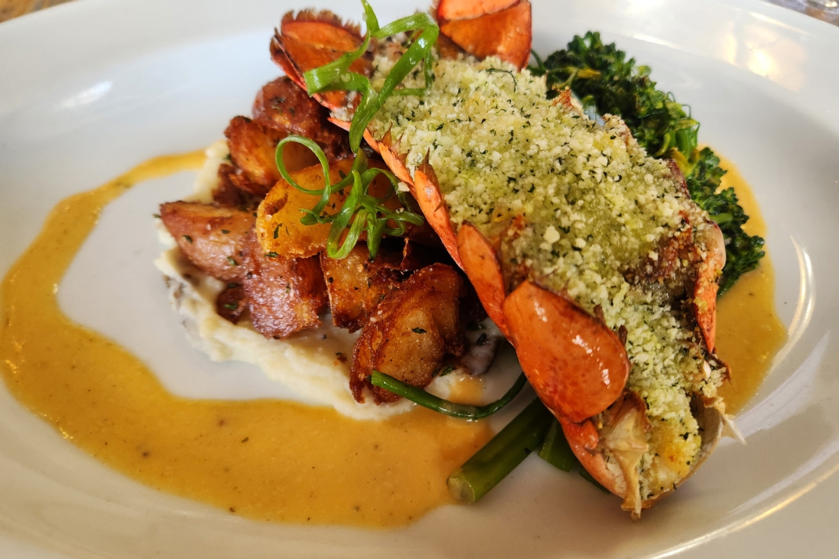 a lobster with vegetables and sauce on a plate