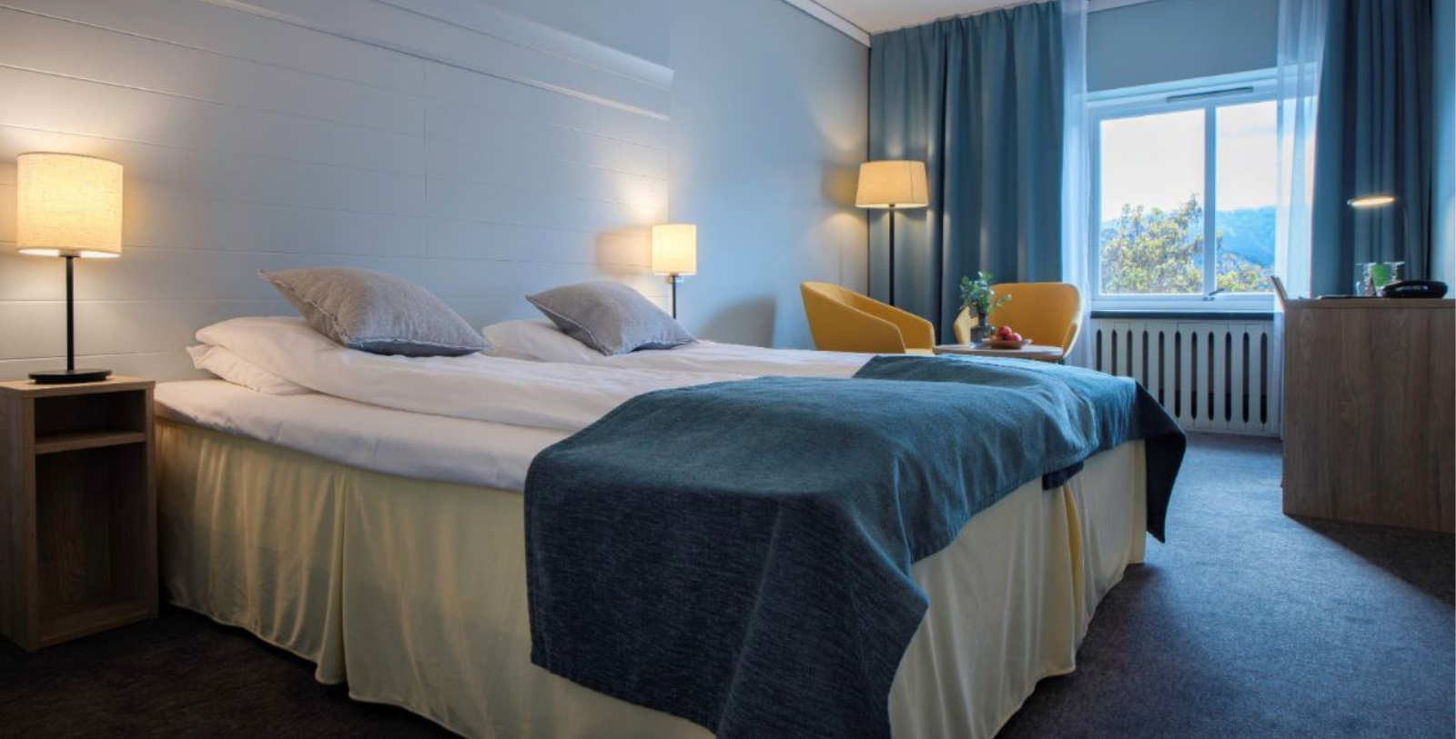 a bed with a blue blanket and a yellow chair