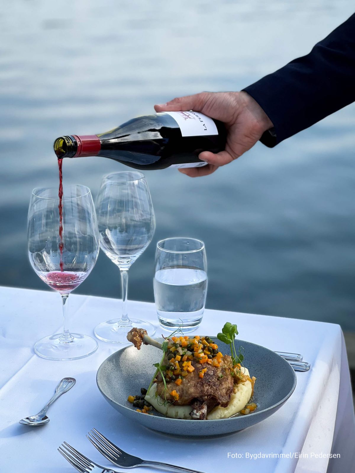 a person pouring wine into a plate of food
