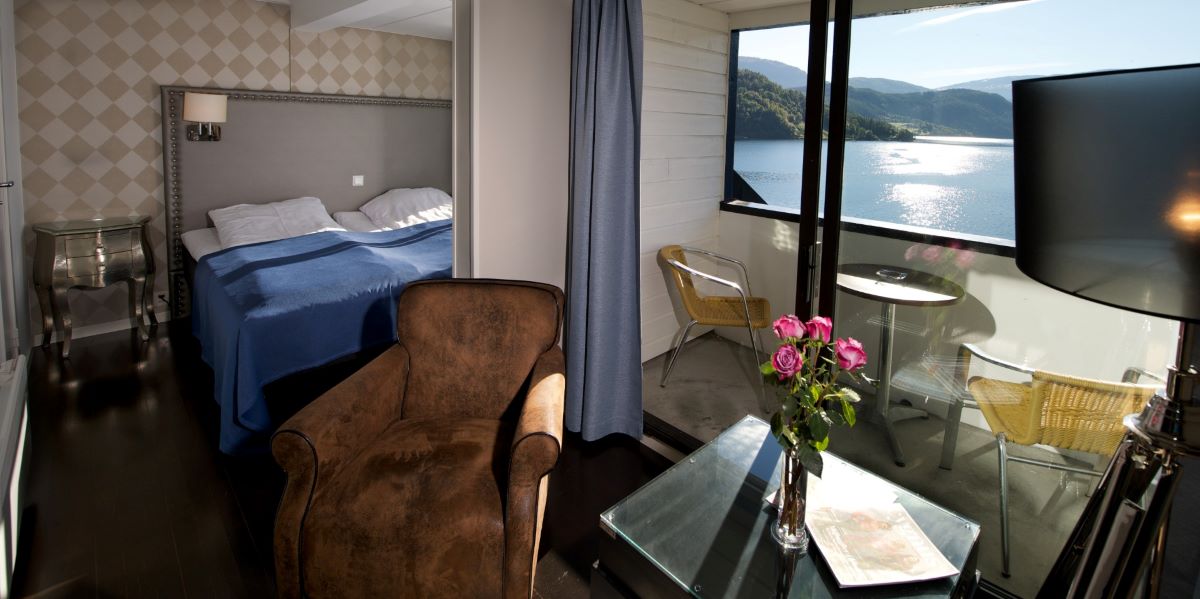 a room with a bed and chairs and a glass table with flowers