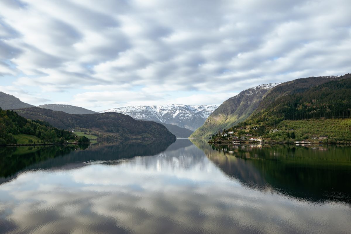 a body of water with mountains and clouds in the sky