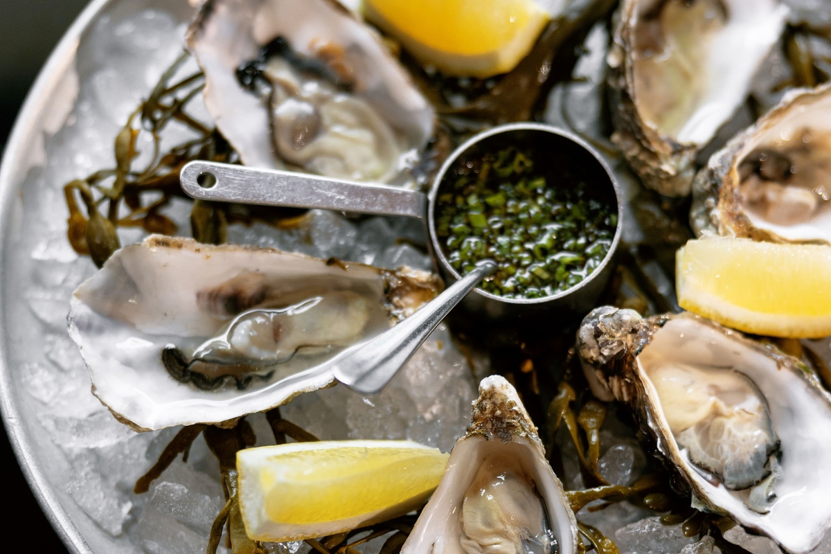 a plate of oysters with lemon and sauce