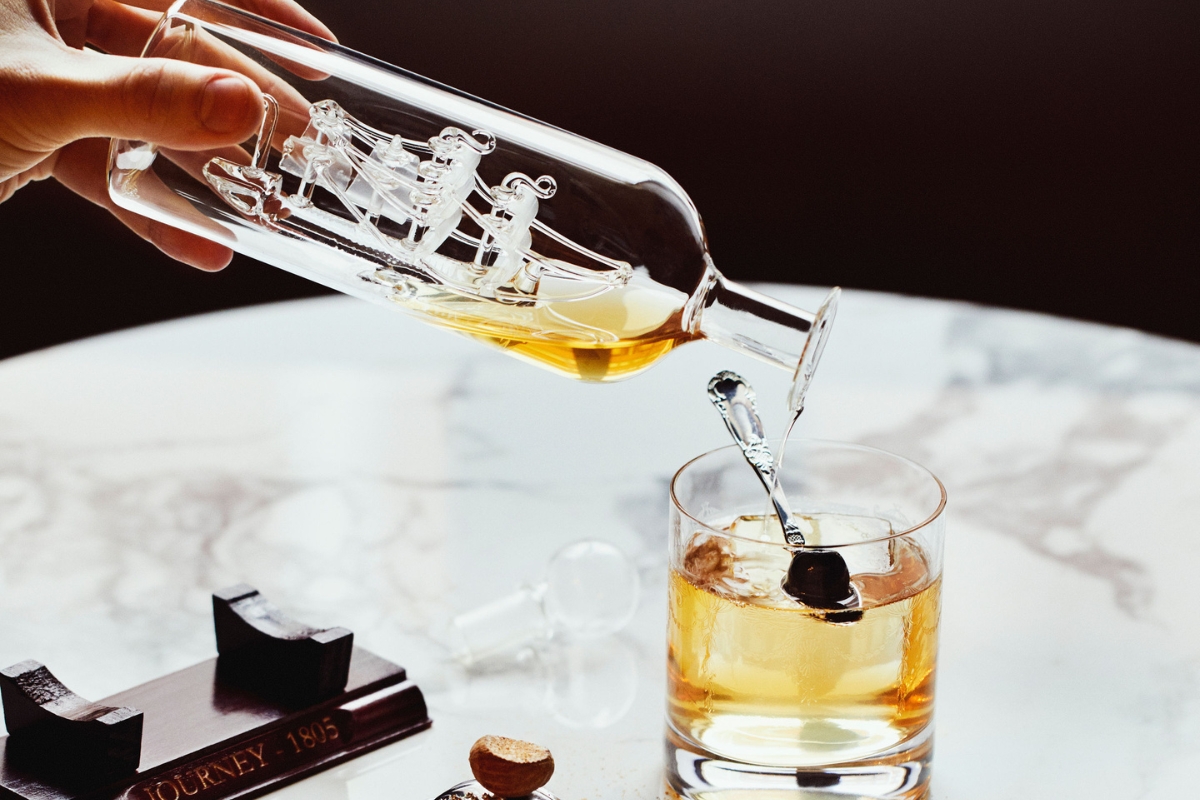a hand pouring a glass of liquid into a glass