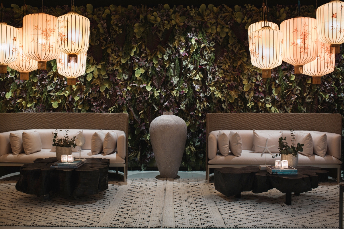 a room with a plant wall and chairs and a vase